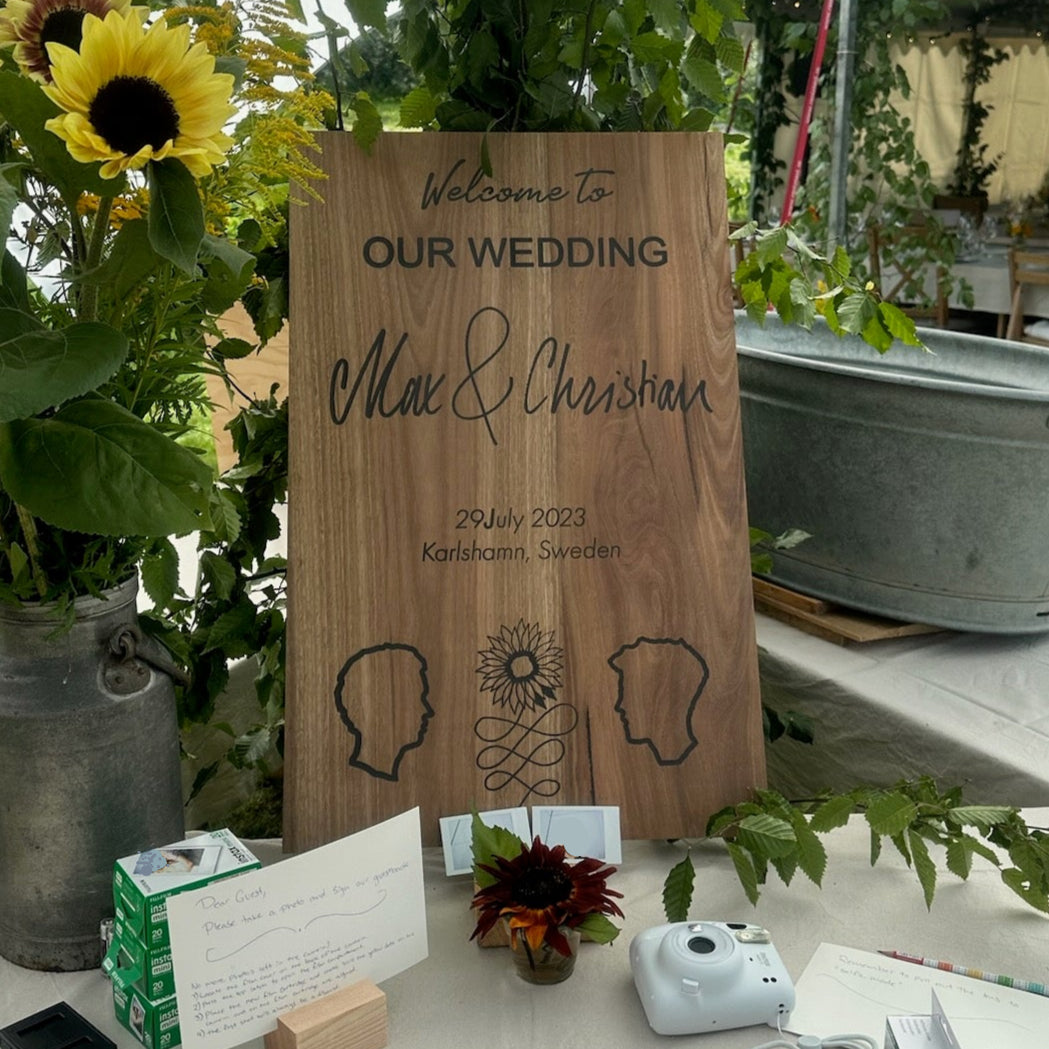 Wedding welcome sign with sunflowers and stationery on a table outdoors.